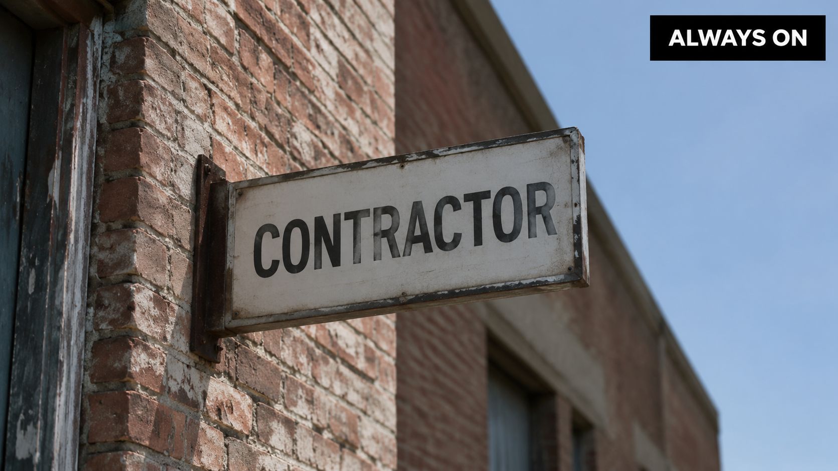 A rectangular sign with the word CONTRACTOR hanging on a weathered brick building wall outdoors.